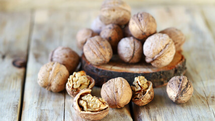 Walnuts in shells on a wooden surface.