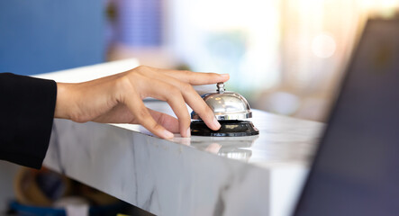 Ring bell call service with hand on hotel reception desk