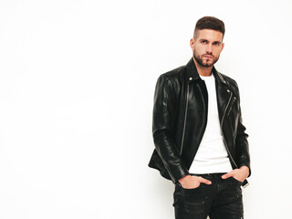 Portrait of handsome confident model. Sexy stylish man dressed in biker leather jacket and black jeans. Fashion hipster male isolated on white in studio