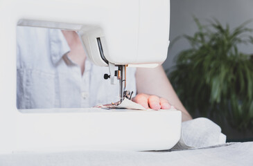 Woman sewing while sitting at her working place in home. Sewing process - Female hands behind her sewing