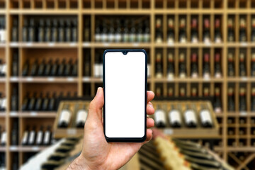 Wine shop with bottles background. Hand with blank smartphone screen one wine backdrop. Buying and...