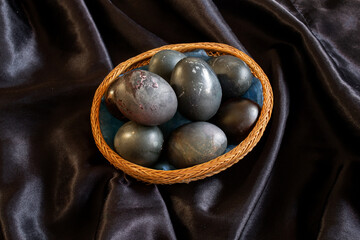 easter-themed photo of black eggs in a wicker plate on a black background