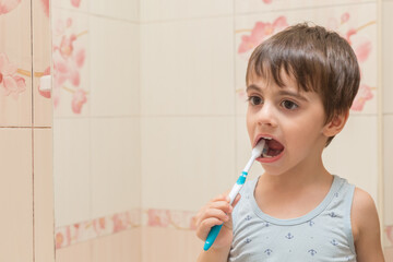 The boy brushes his teeth with a toothbrush.