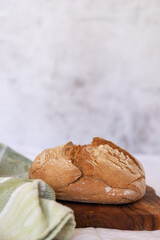 A round organic wheat bread on a wooden cutting board close-up