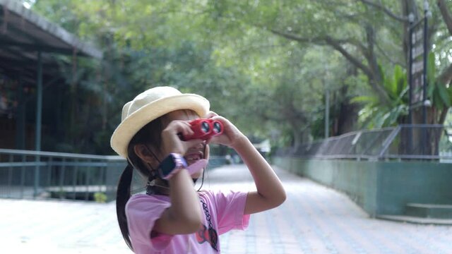 Slow motion scene of A 5-year-old Asian girl is learning about the nature around her. with binoculars