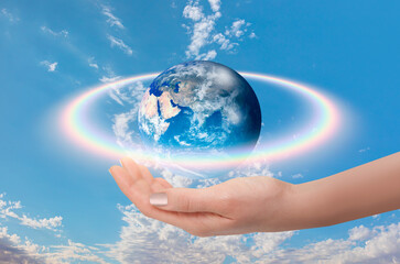 Rainbow surrounds the Planet Earth with woman hand 
