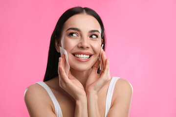 Beautiful woman using mattifying wipes on pink background, space for text