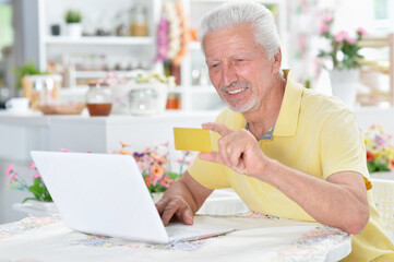 portrait of beautiful senior man using laptop at home