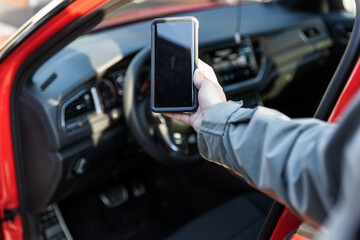 Woman using smartphone in front of the car. Communication or connect to an app. Car sharing, rental...