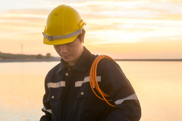 A male engineer wearing a protective helmet at sunset..