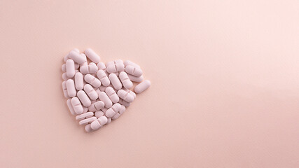 Heart made of pills on pink background. Creative concept for Valentine's Day or Pharmacy, Dietary Supplement and Cardio Medicines.