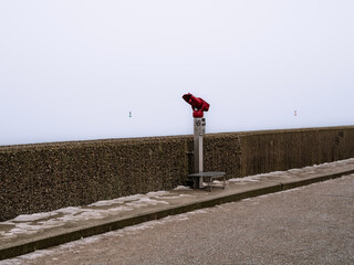 Travemünde, Germany, 29 December 2021. Binocularas on the harbor mole pointed towards a cloudy and misty sea.
