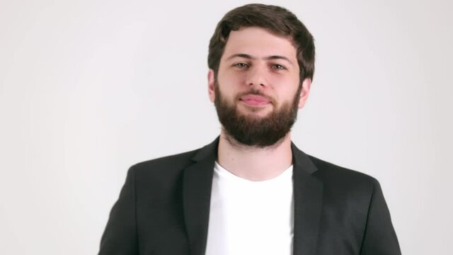 Look of a satisfied, caucasian man with a beard in black suit on white background 4K. Emotions, facial expressions, gesture