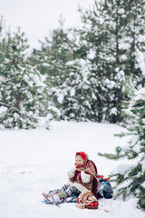 Fototapeta na wymiar Beautiful little child girl plays in snowy forest in red headscarf.
