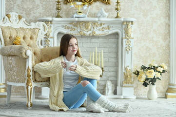 Obraz premium Portrait of beautiful teen girl with cup of tea sitting on floor