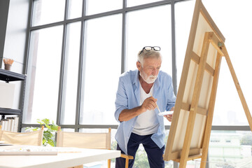 senior man painting a picture from paintbrush in free time
