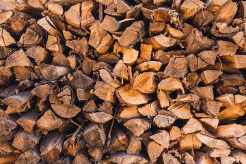 texture background of stacked brown firewoods on a sunny day in the forest