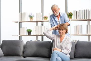 senior man giving a hand massage to his wife on sofa