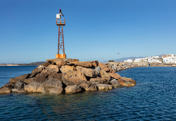 Beacon old rusty on rocky construction at Naoussa village harbor Paros island Cyclades Greece.