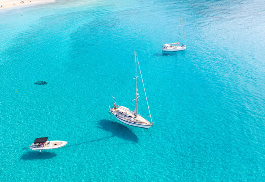 Boats anchored on calm turquoise sea water background, aerial drone view