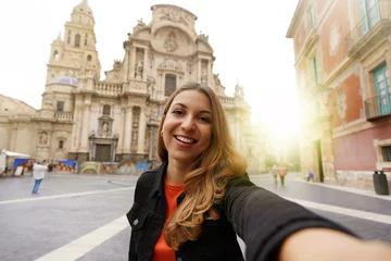 Foto op Canvas Smiling girl in Murcia taking selfie photo with the Cathedral Church of Saint Mary and cityscape on the background. Girl takes self portrait in Murcia, Spain. © zigres