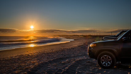 Fototapeta na wymiar cars on the empty ocean beach during sunset 