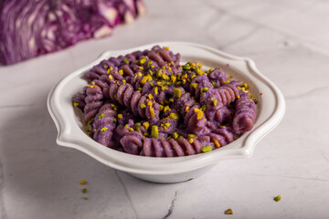 Fusilli pasta with purple cabbage cream and chopped pistachios. Dish suitable for a vegan diet.