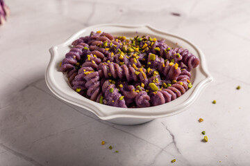 Fusilli pasta with purple cabbage cream and chopped pistachios. Dish suitable for a vegan diet.