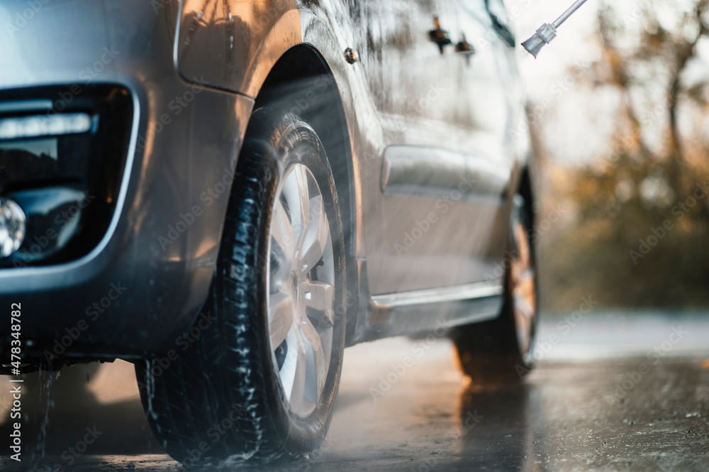 Poster Manual car wash with white soap, foam on the body. Washing Car Using High Pressure Water.