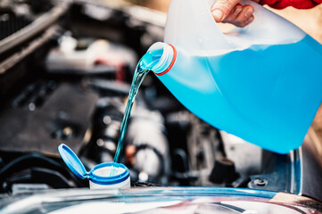 Pouring antifreeze. Filling a windshield washer tank with an antifreeze in winter cold weather.