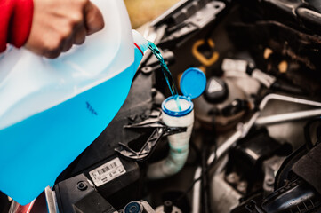Pouring antifreeze. Filling a windshield washer tank with an antifreeze in winter cold weather.