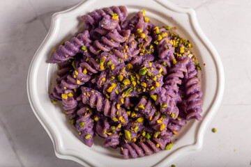 Fusilli pasta with purple cabbage cream and chopped pistachios. Dish suitable for a vegan diet.
