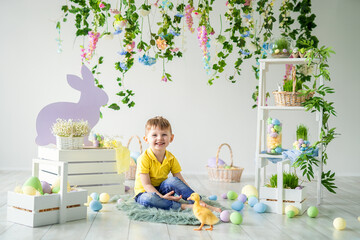 Obraz na płótnie Canvas Happy little boy sits on wooden floor with little duckling in Easter decoration. Easter for children