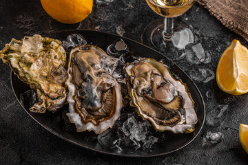 Fresh oysters close-up on ice served with lemon and wine.