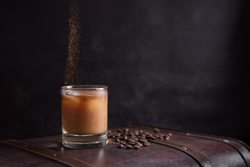 Vaso de café helado con canela y granos de café en una vieja maleta marrón