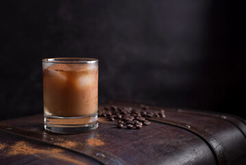 Vaso de café helado con canela y granos de café en una vieja maleta marrón