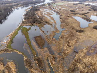 A spilled river in a floodplain during a thaw on a cloudy day.
