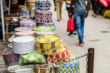 African traditional hats kofias for sale at the bazaar market in Stone town. Zanzibar island, Tanzania - obrazy, fototapety, plakaty