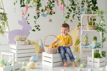 Obraz na płótnie Canvas Happy Little boy sits near the basket with fluffy ducklings on the wooden box. Easter decoration. 