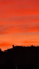 Genova, Italy - January 1, 2021: An amazing photography of the sunset in winter days over the sea and the port of Genova with beautiful red sky and some amazing coloured clouds in the background.