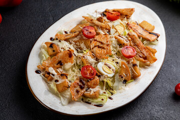 Caesar salad served on a white plate. dark background decorated with food