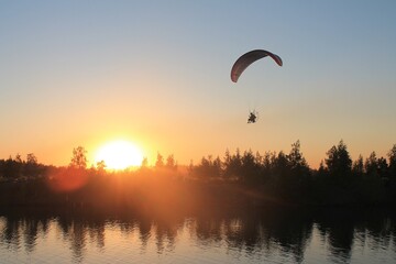 A hang glider flies into the sunset