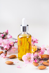 Obraz na płótnie Canvas Almond essential oil in a bottles with spring blossom branches