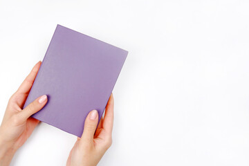 The girl is holding a blue-purple book or notebook (the fashionable color of 2022) on a white...