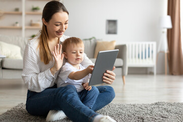 Young mother and toddler son making video call with tablet, woman waving hand at webcamera and smiling
