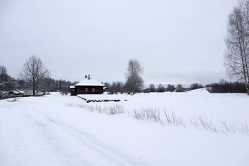 snow covered old brown wooden house in the winter field