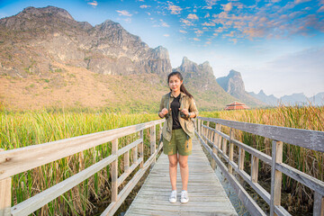 Fototapeta na wymiar Freedom traveler woman standing with raised arms and enjoying a beautiful nature and cheering young woman backpacker at sunrise seaside mountain peak 