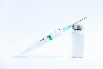 The vaccines vials glass bottle and disposable syringe on white