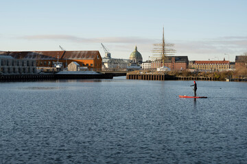 A man is engaged in water sports against the backdrop of a Danish cityscape