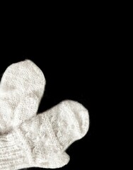 White natural handmade wool mittens on a black background with copy space